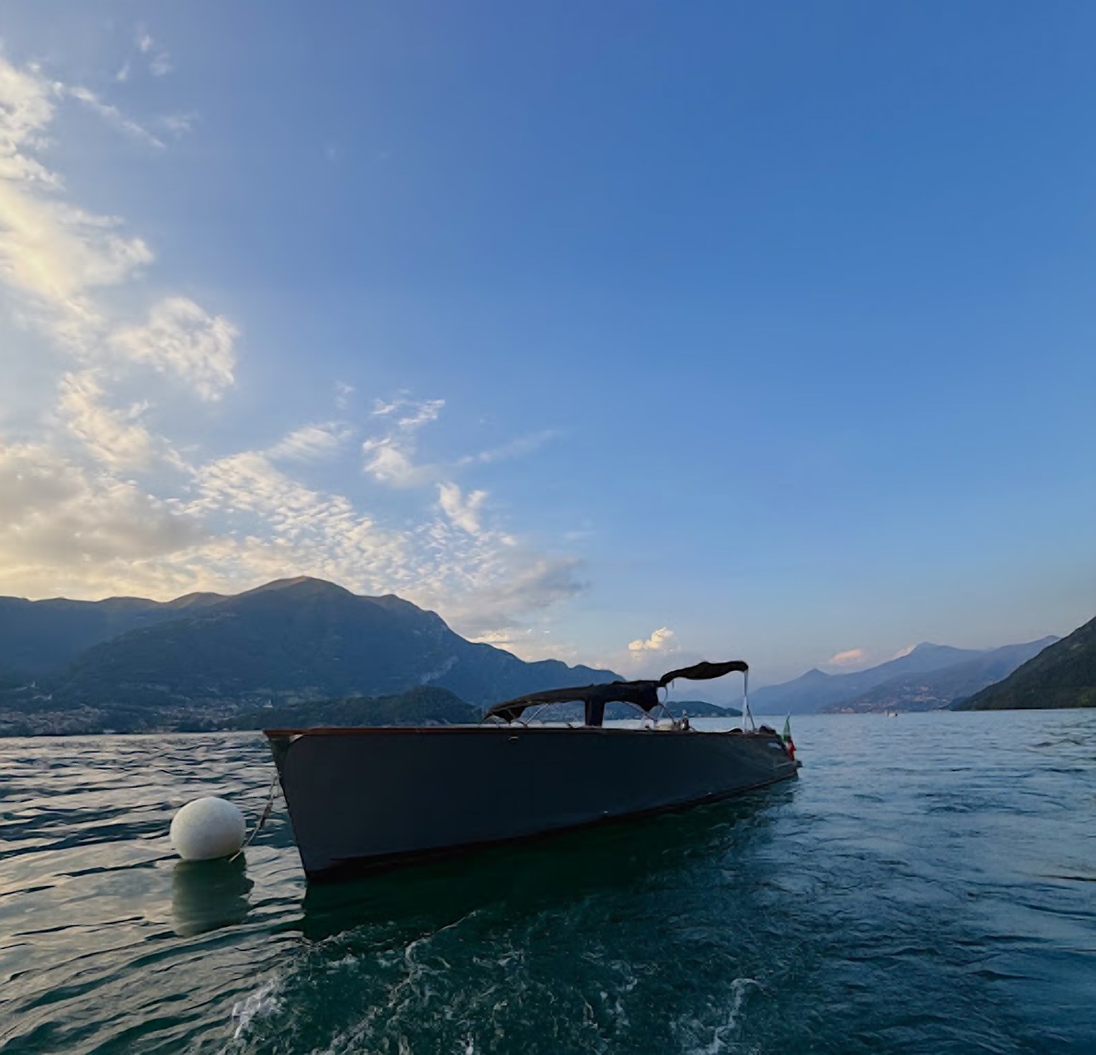 The Cooper 800 moored at golden hour on Lake Como, its dark hull against the mountains of the western shore