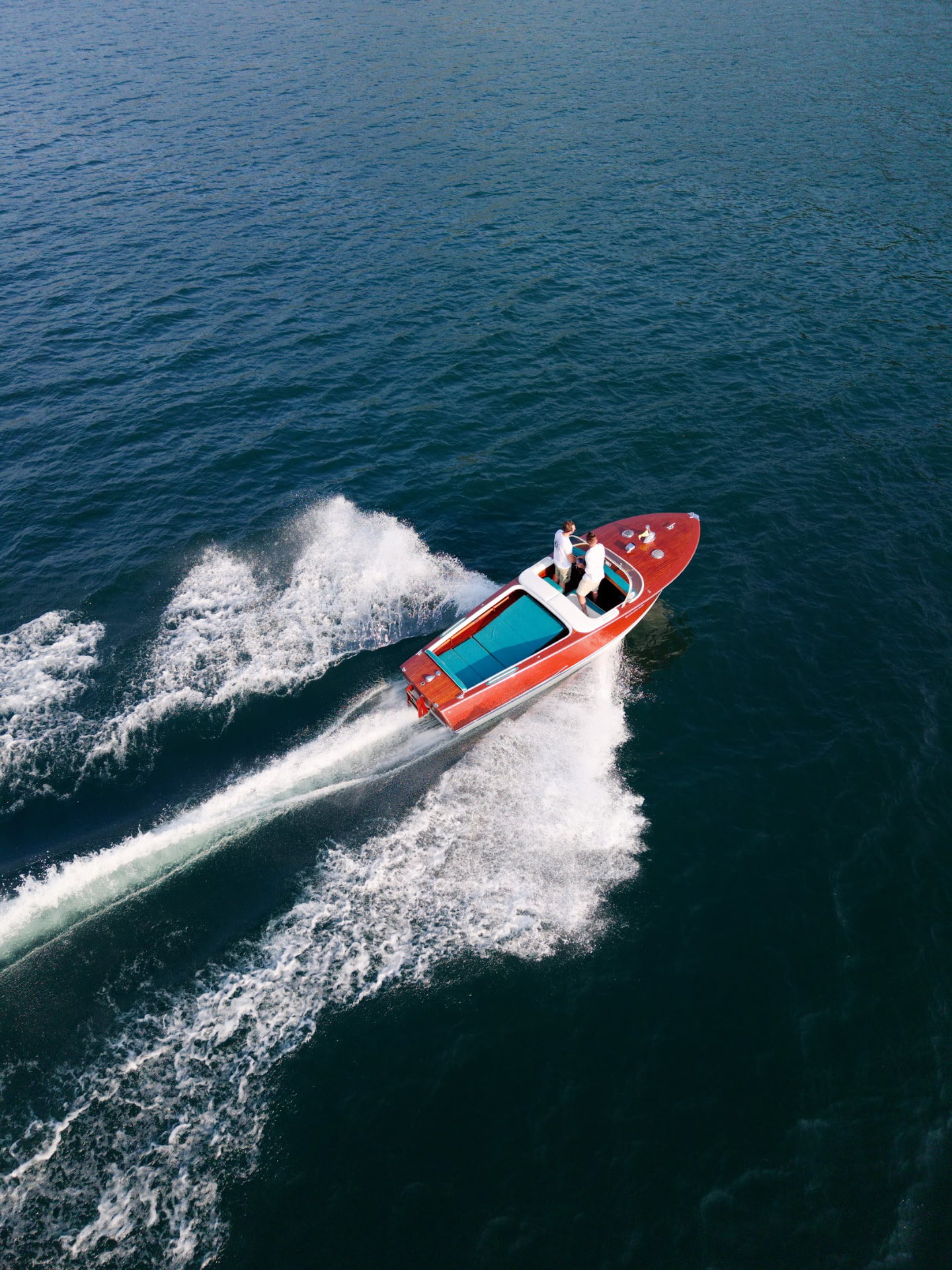 Classic wooden boat gliding on Lake Como, seen from above