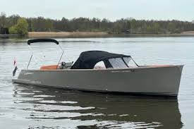 The Cooper 800 with its bimini top raised, lying still on calm water