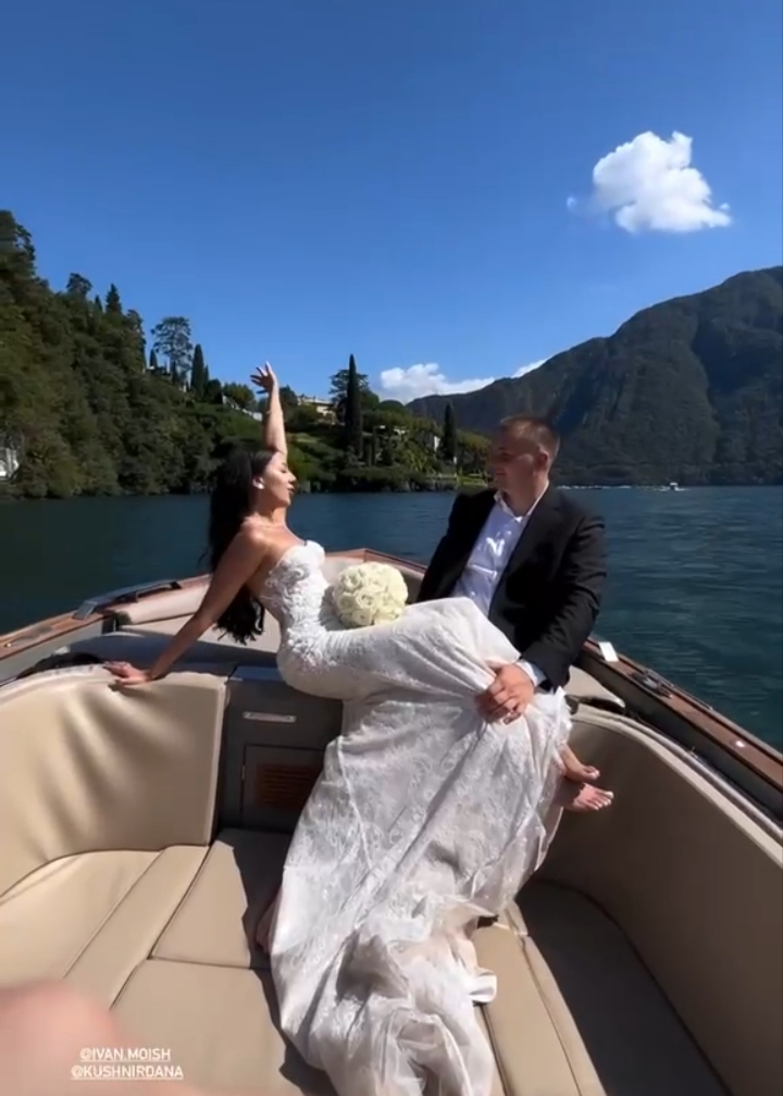 Newlywed couple relaxing aboard a classic wooden boat on Lake Como, villas and mountains beyond