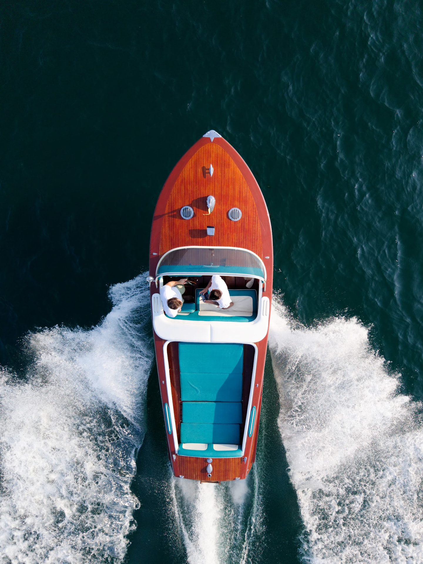 Top-down view of the polished wooden event boat and turquoise cockpit